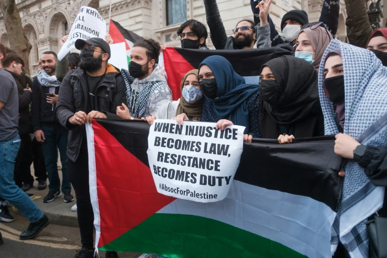 people hold flags and posters as they march in protest