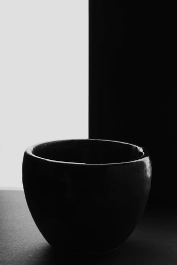 a black bowl sits on a table next to a white wall
