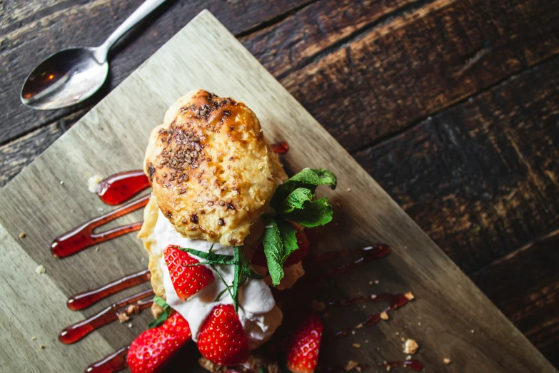 pastry with some strawberries and whipped cream on a  board