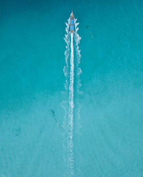 an aerial view of a boat in the blue water