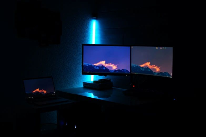 the computer desk with the laptop is set on in the dark