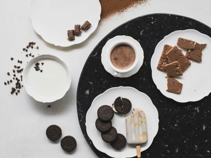 a table with chocolate slices, cookies and milk