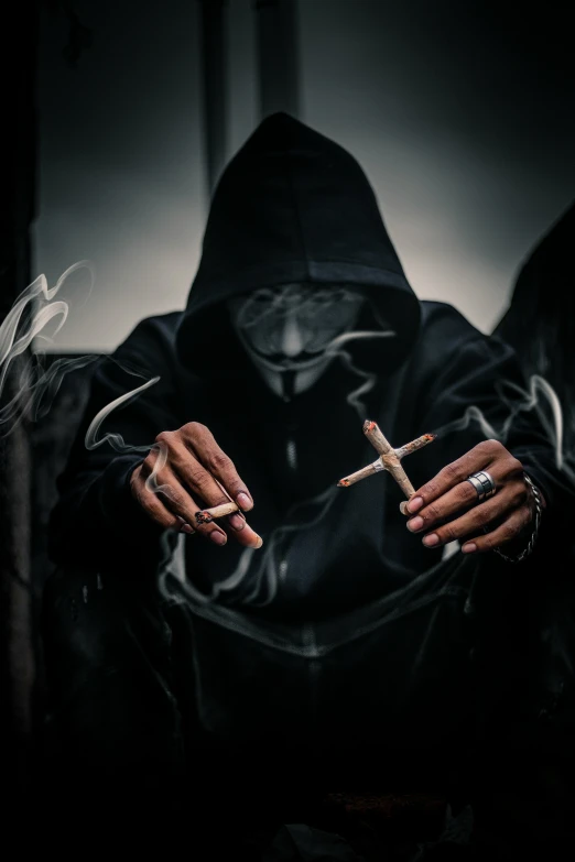 a black hooded woman smoking and holding a cigarette