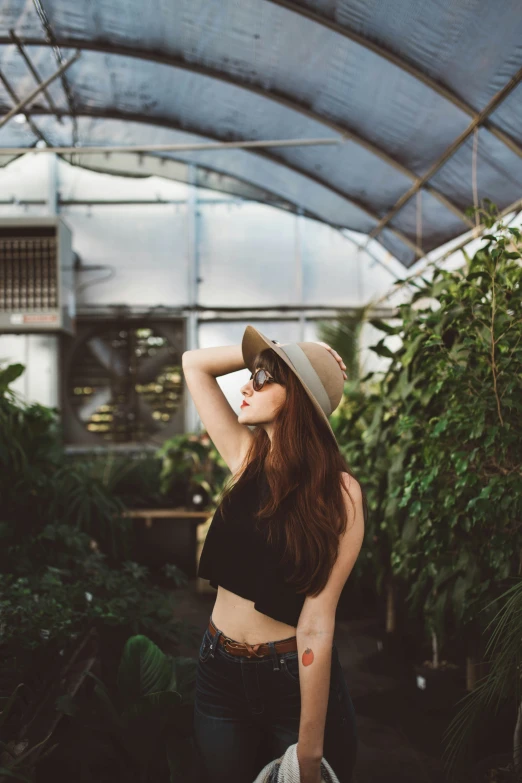 a beautiful woman wearing glasses standing in a greenhouse