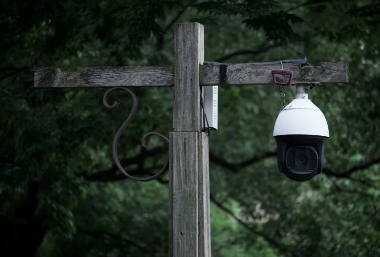 a white camera mounted to the side of a wooden pole