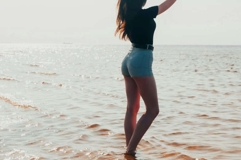 a girl standing on top of a beach next to the ocean