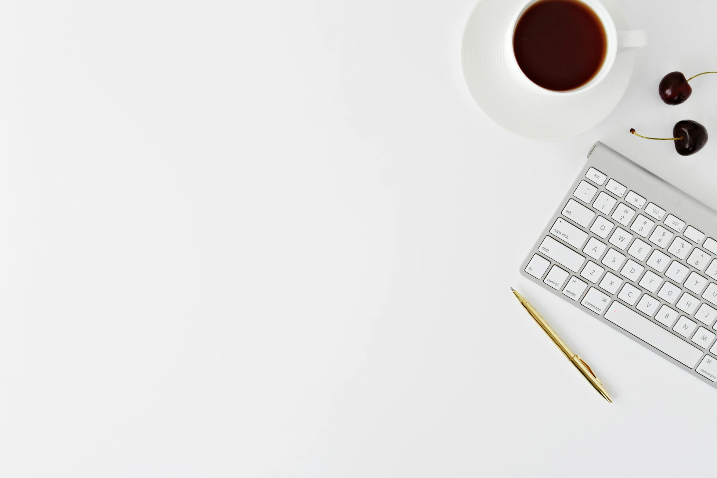 white and black desktop with computer keyboard, mouse and cherries