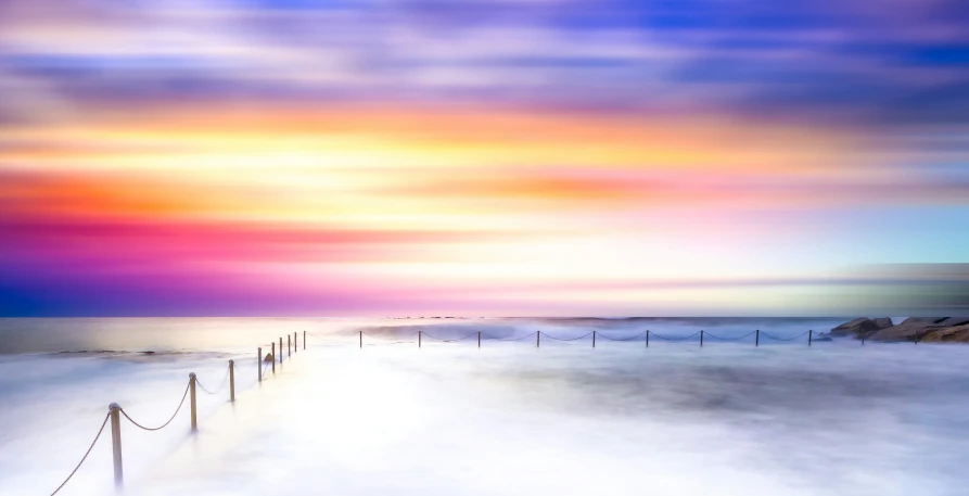 a long wooden fence next to some sand and water