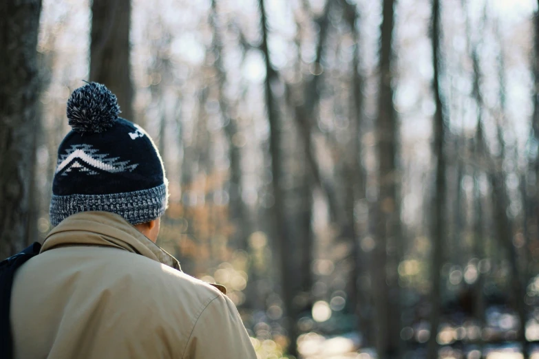 a man wearing a blue beanie walks in the woods