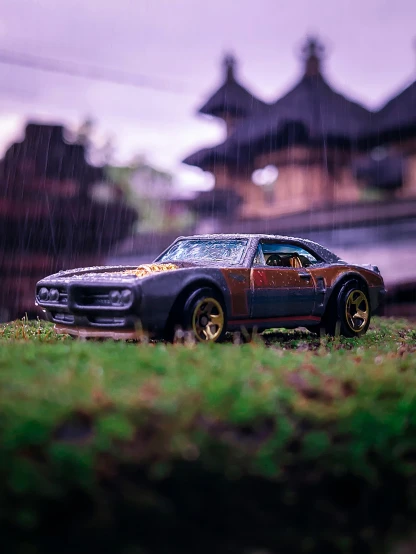 a toy car with rain on the windshield sits in a yard