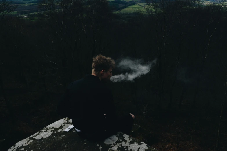 a person sitting on a rock smoking a pipe