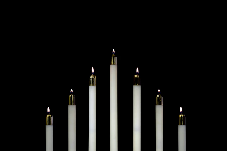 five candles with one lit and the other on black