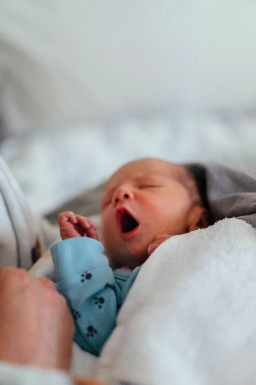 a baby in blue wrapped up asleep on a bed