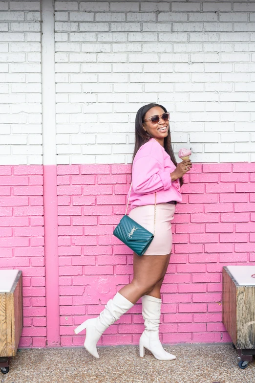 the young woman is standing against a pink wall