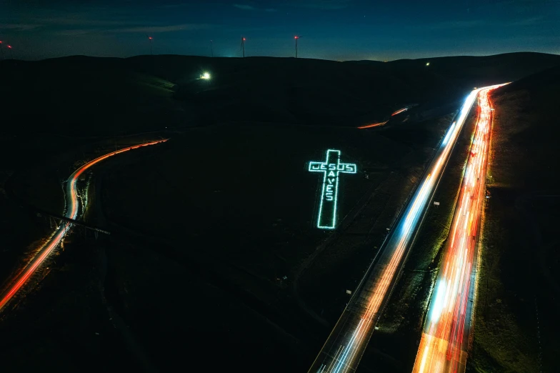 a road with bright lights at night next to a cross