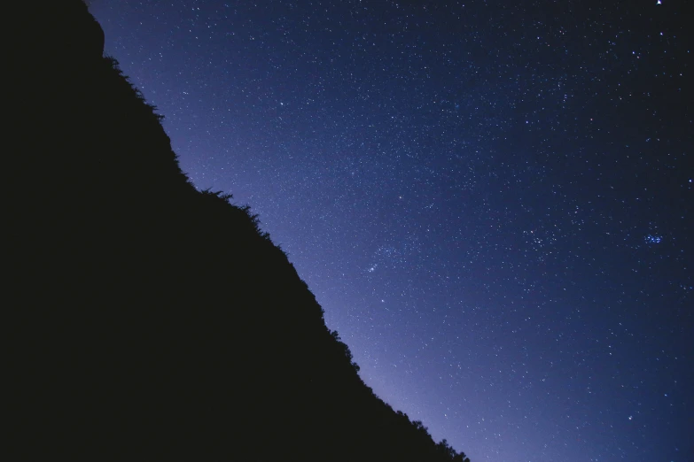 the sky over mountains and a night time sky