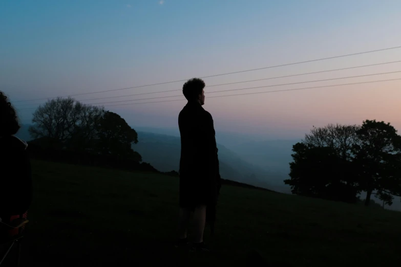 two people look up at the sky while the sun sets