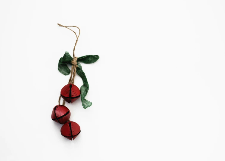 three small red berries tied together by a green ribbon