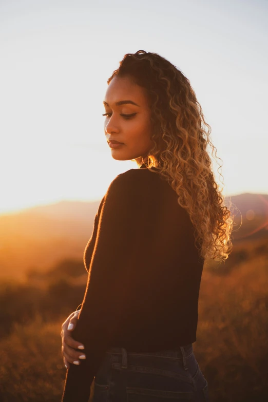 a woman with curly hair standing in a field