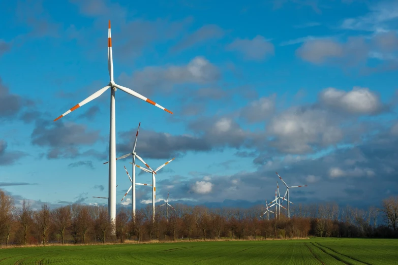 several wind turbines sitting in the grass with blue skies above