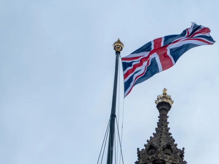 a flag flying from top of a tall tower with a clock