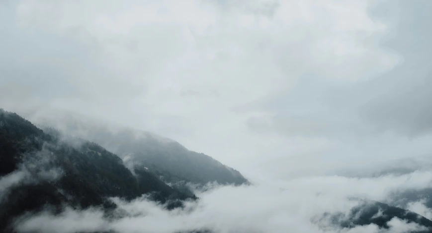 mountains are obscured by white clouds during the day