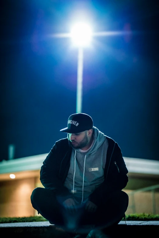 a man sitting on the ground while holding his hat