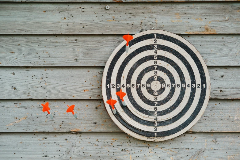 a close up of a bulls eye target with arrows on a wooden wall