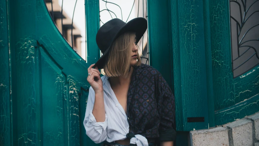 woman in traditional costume and hat leaning against green door