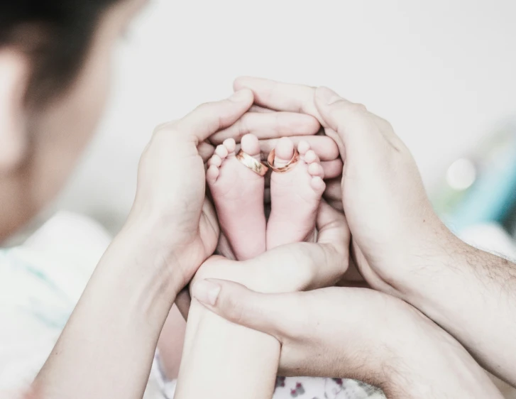 two hands are holding the feet of a baby