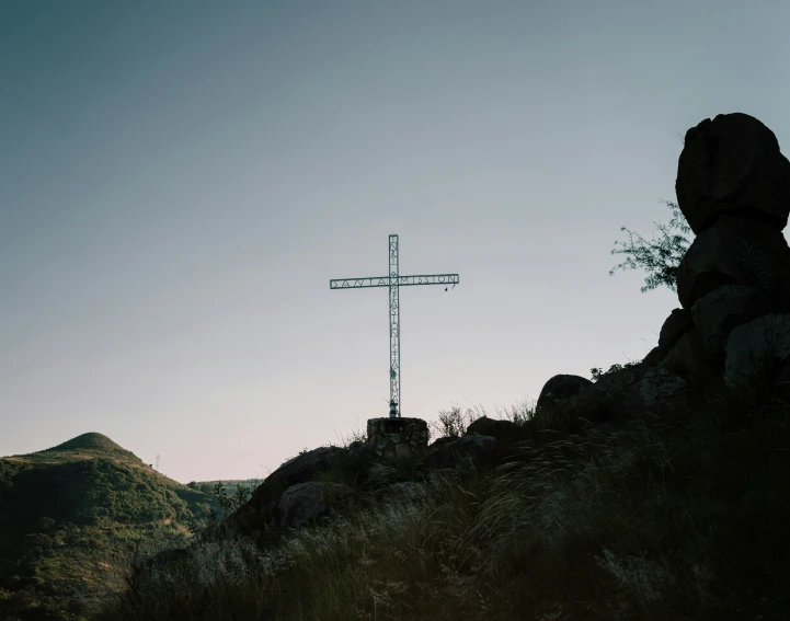 a cross on top of a hill with a lot of rocks