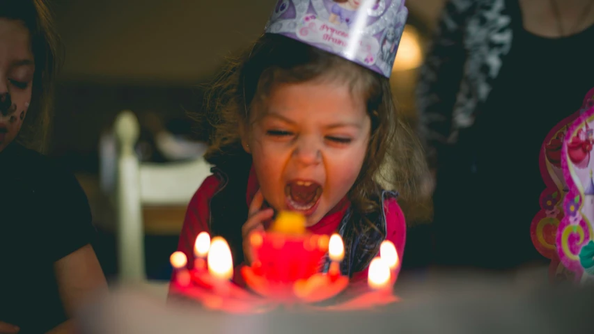 a  blowing out candles on a birthday cake