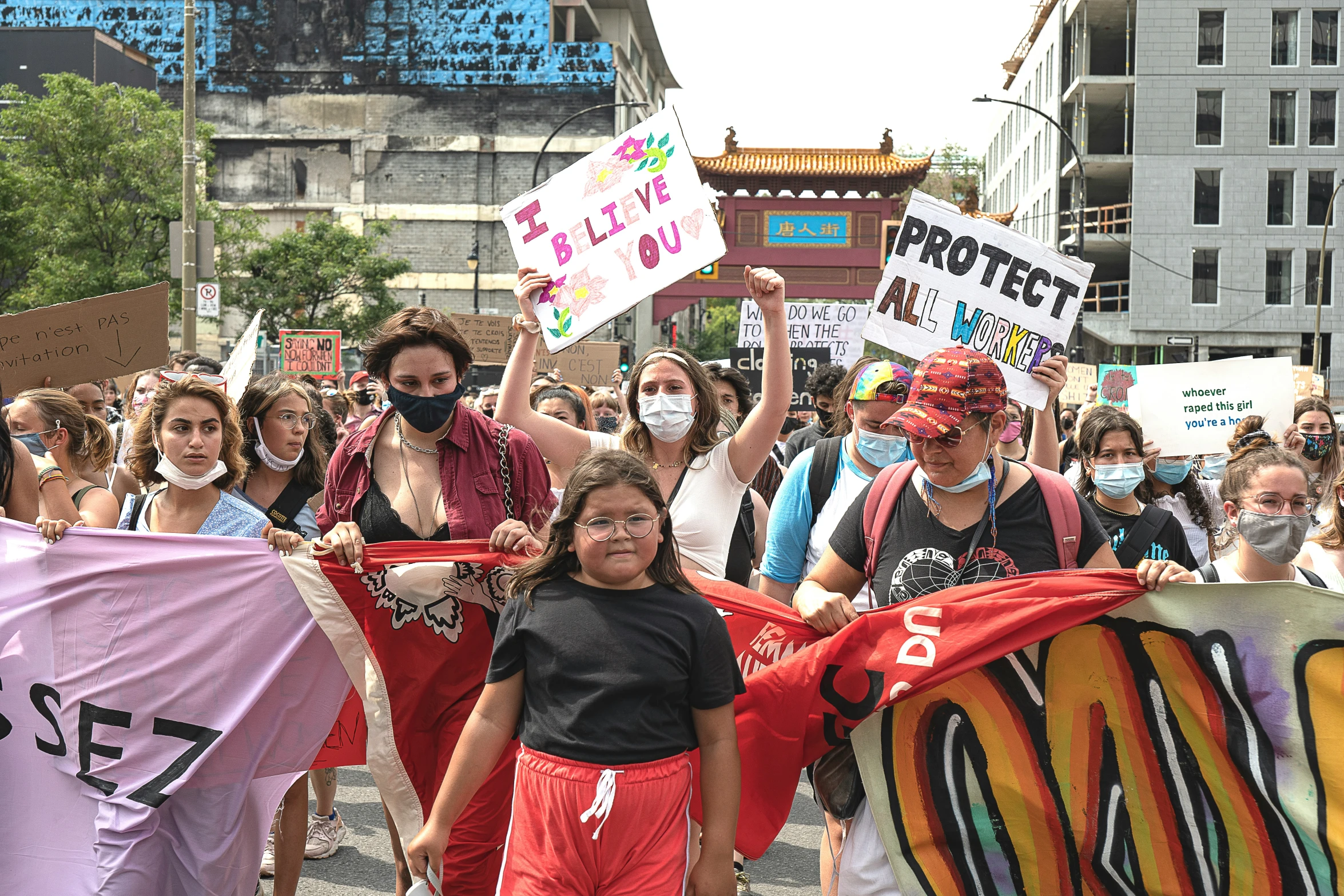 people marching with red banner, with faces obscured by the signs