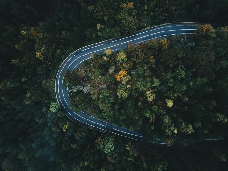 an aerial view of a winding road in the forest