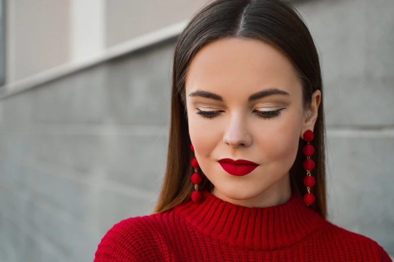 a woman wearing long red earrings and lipstick