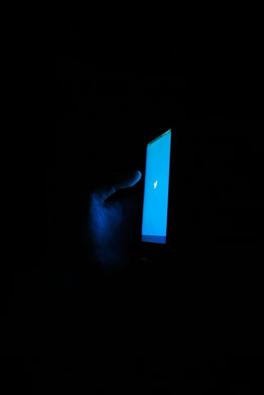 a dark room with a person holding a lit up cell phone