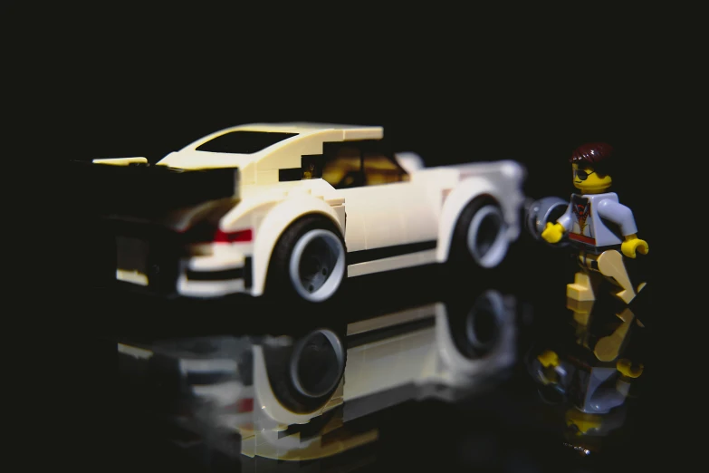 toy lego man holding an unopened car with reflection