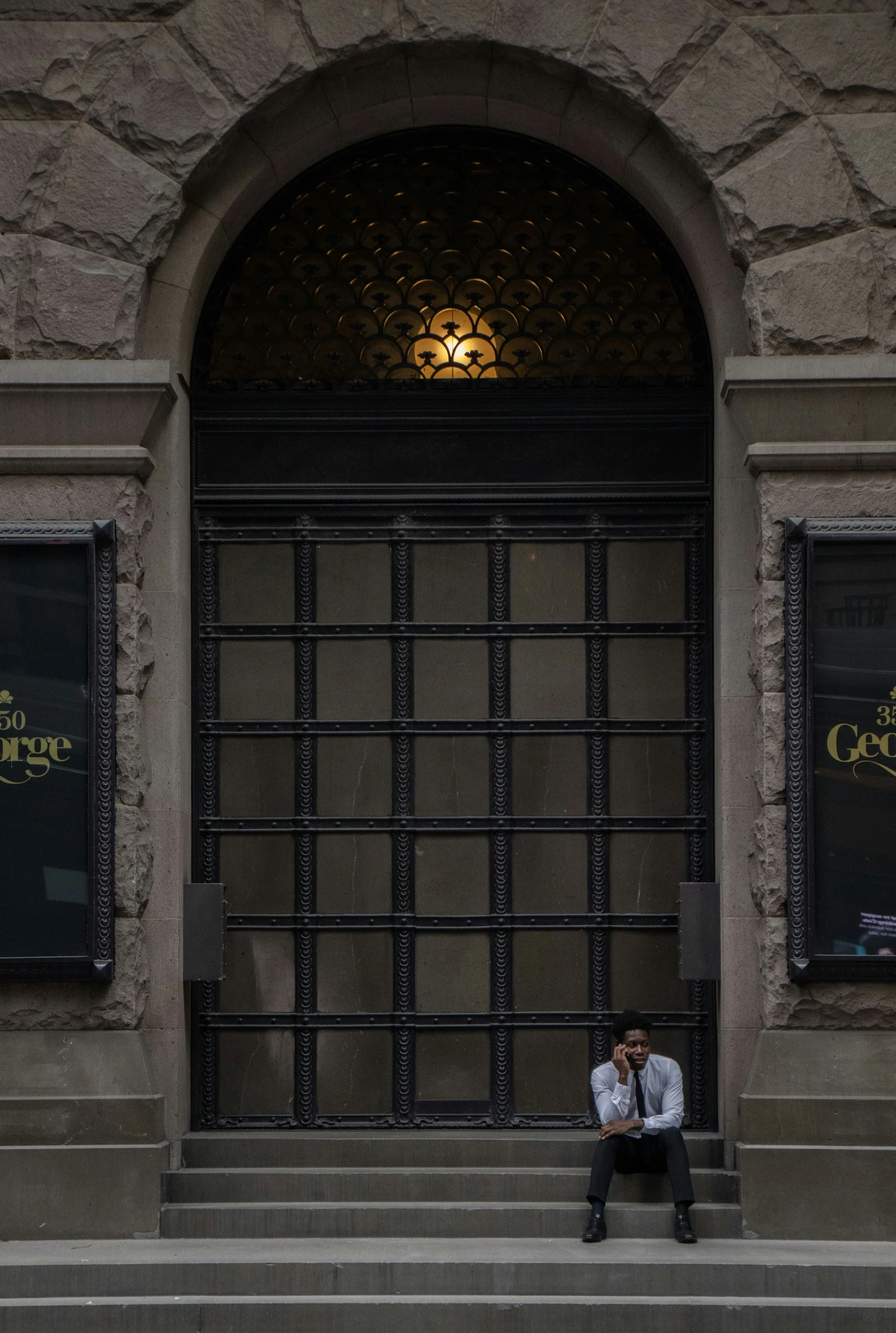 a man in shirt sitting on step of building near window