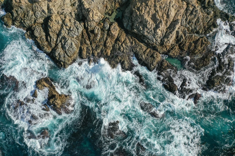 an aerial view of a rocky shore next to the ocean