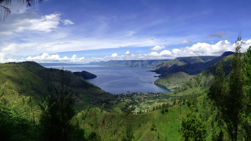 a lake surrounded by some green mountains