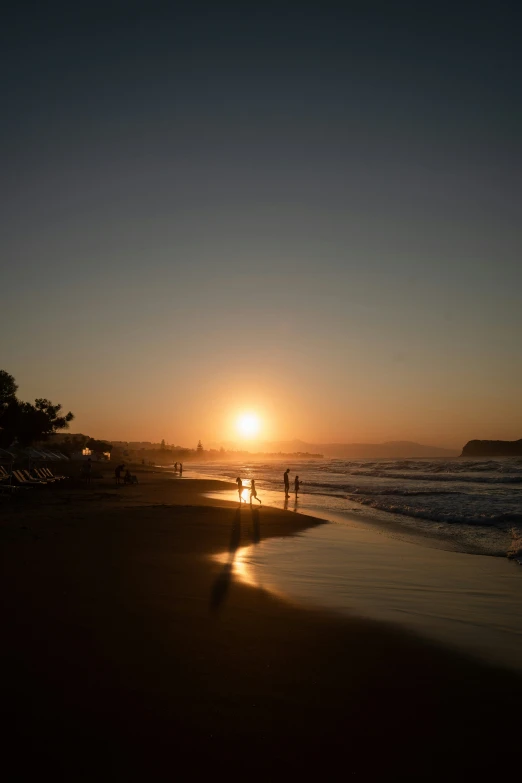 two people walking on the beach at sunset