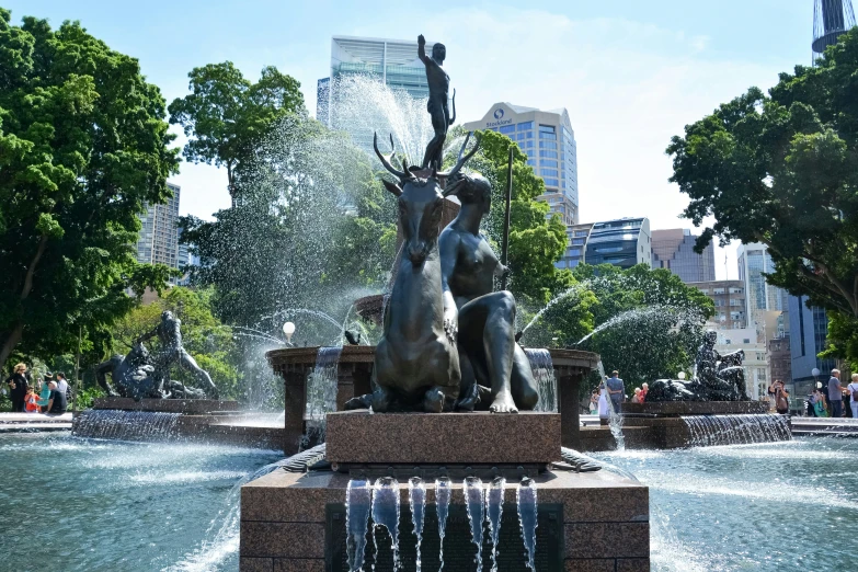 the water fountain in the park is decorated with bronze statues