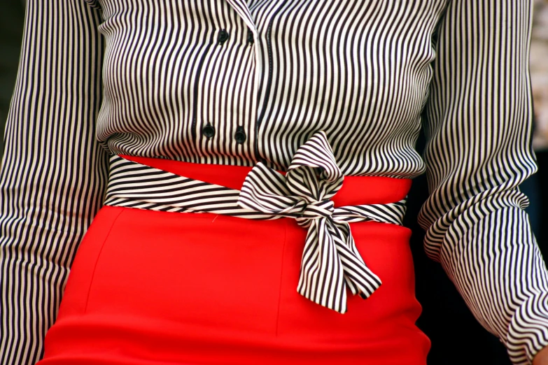 a woman in a red skirt holding a black and white striped shirt