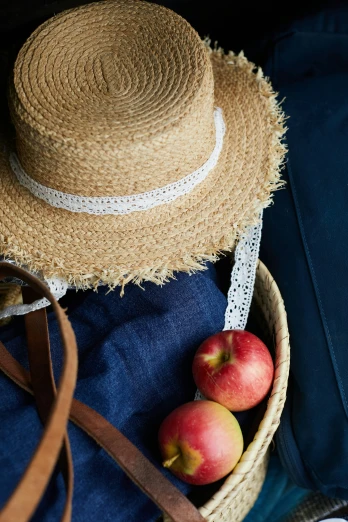 a straw hat, red apples, and blue fabric