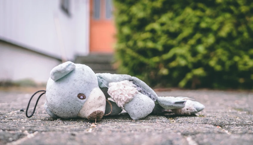 an old teddy bear sits on the ground