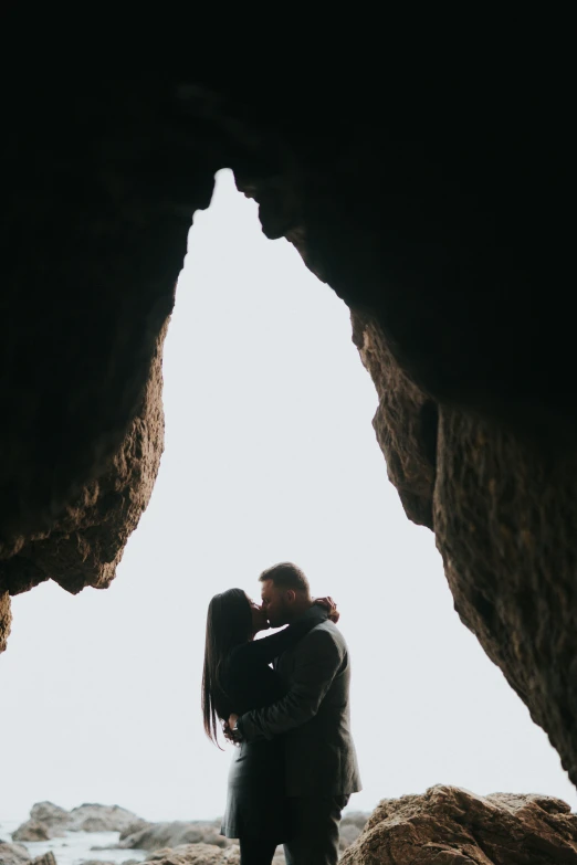 a couple stands in the middle of a cave