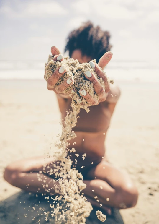 a girl is covered in sand while sitting on the beach