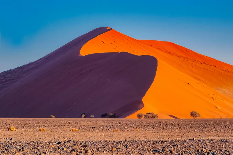 a big orange mountain near some trees and rocks