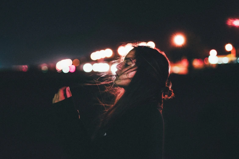 a girl in the street at night gazing at light