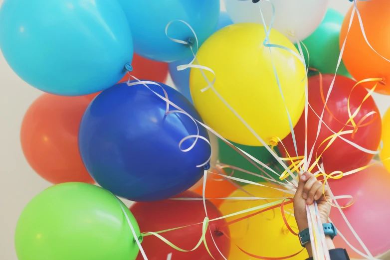 someone holding onto a bunch of balloons in the air